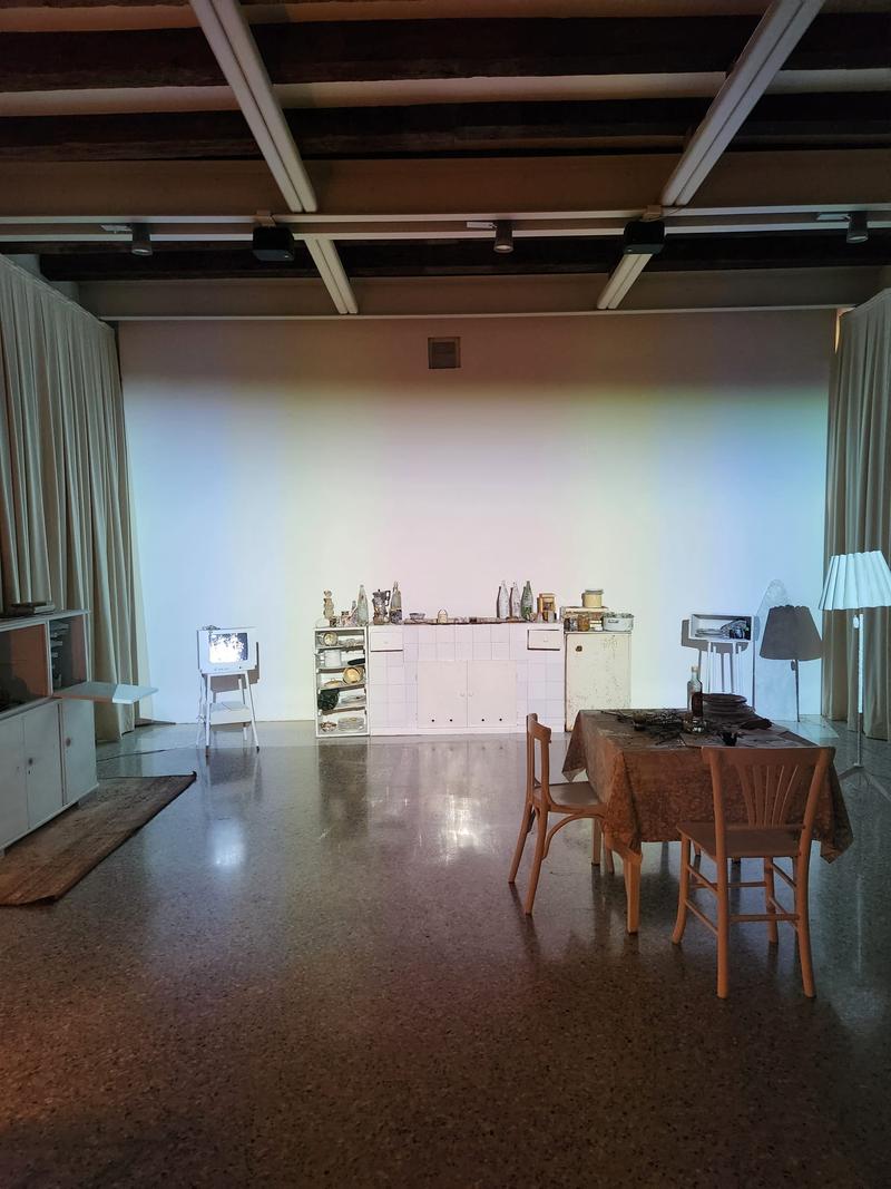 The Neighbours installation setup at Sala Tiziano in Venice, showing domestic furniture, lighting, and CRT TV